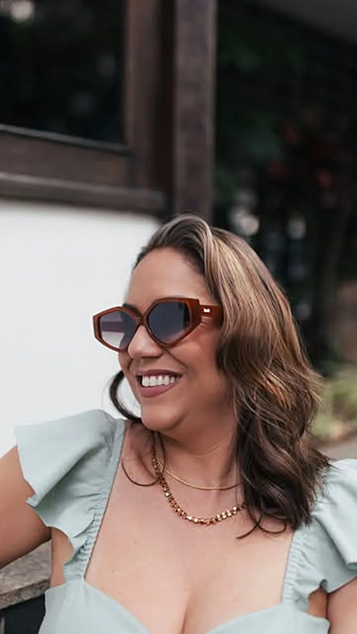 Mulher sorrindo com óculos de sol de armação marrom